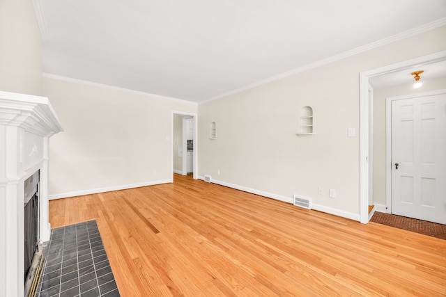 unfurnished living room featuring wood finished floors, a fireplace with flush hearth, visible vents, and crown molding