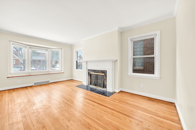 unfurnished living room featuring light wood finished floors, baseboards, a fireplace, and visible vents