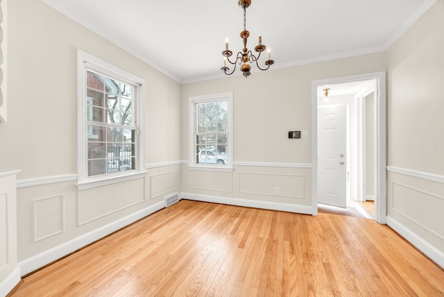 unfurnished dining area with crown molding, visible vents, a notable chandelier, and hardwood / wood-style flooring