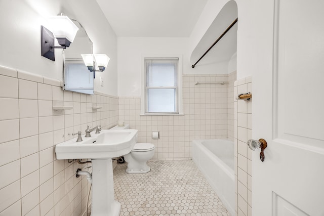 full bathroom with toilet, a wainscoted wall,  shower combination, tile patterned flooring, and tile walls