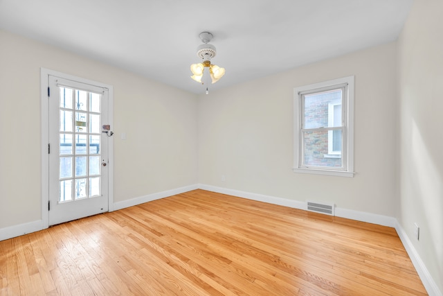 unfurnished room with visible vents, light wood-style flooring, and baseboards