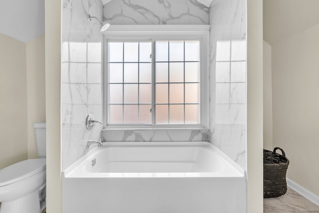 bathroom featuring marble finish floor, toilet, and a bathing tub