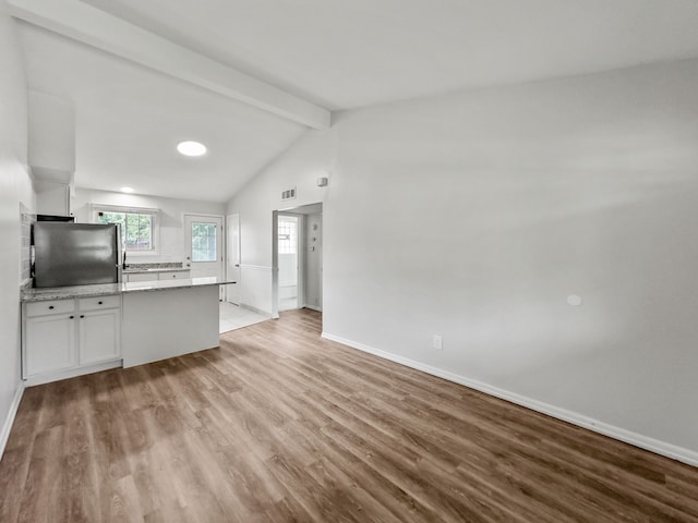 kitchen featuring light wood-style flooring, baseboards, white cabinets, light countertops, and freestanding refrigerator