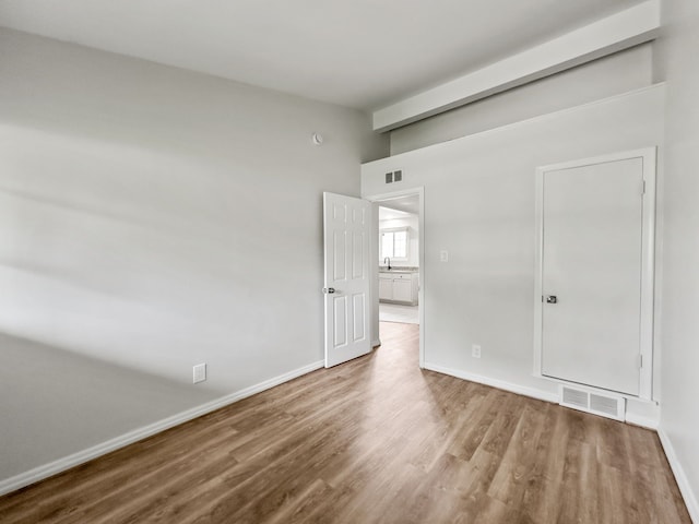 unfurnished room featuring baseboards, visible vents, and wood finished floors