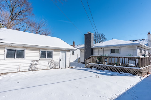 snow covered rear of property with a wooden deck