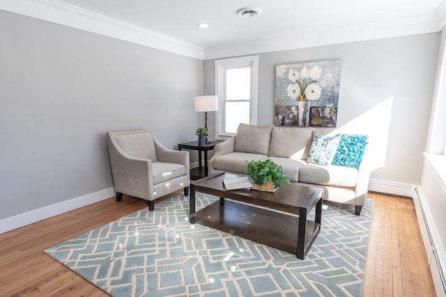 living room with ornamental molding, a baseboard radiator, baseboards, and wood finished floors