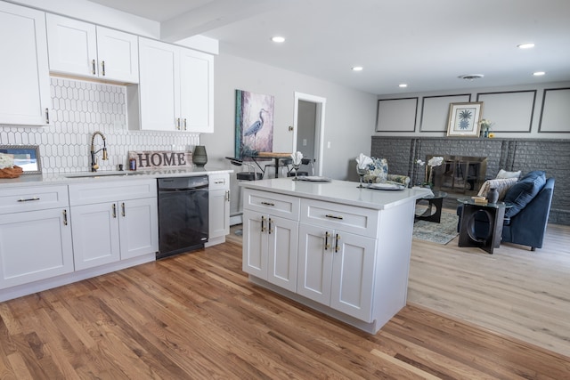 kitchen with black dishwasher, light countertops, a sink, and white cabinets