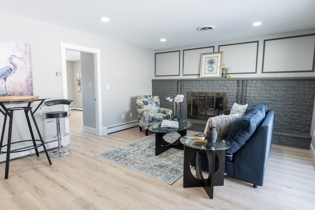 living area with light wood-type flooring, visible vents, a fireplace, and baseboard heating