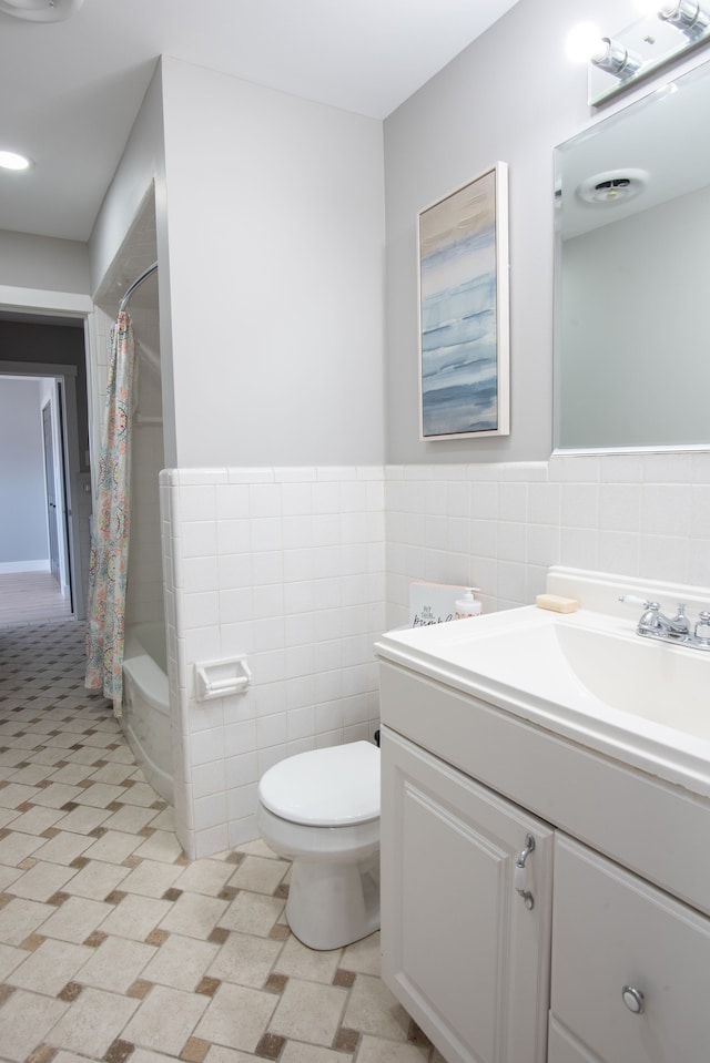 bathroom featuring toilet, wainscoting, tile walls, and vanity