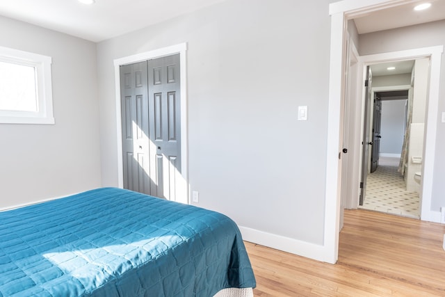 bedroom with a closet, recessed lighting, wood finished floors, and baseboards