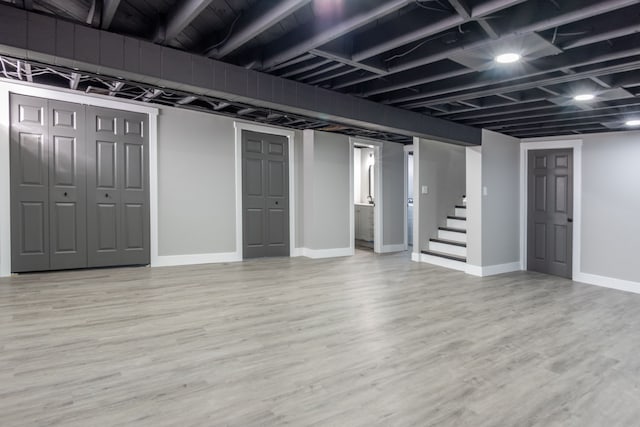 finished below grade area with stairway, baseboards, and wood finished floors