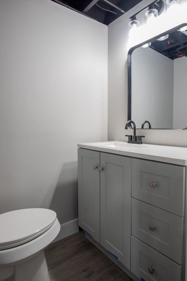 bathroom with toilet, baseboards, wood finished floors, and vanity