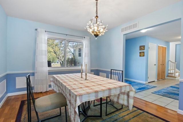 dining area featuring baseboards, visible vents, a chandelier, and wood finished floors