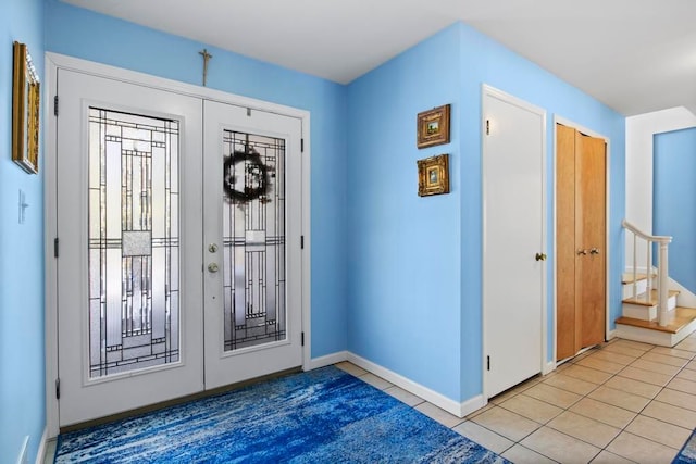 entryway featuring light tile patterned floors, stairs, baseboards, and french doors