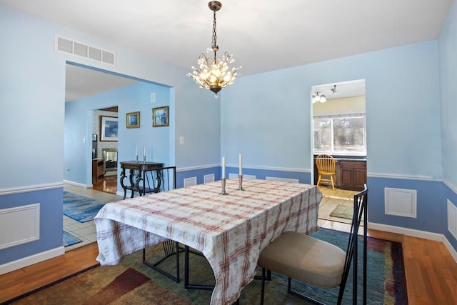 dining room with visible vents, a notable chandelier, baseboards, and wood finished floors