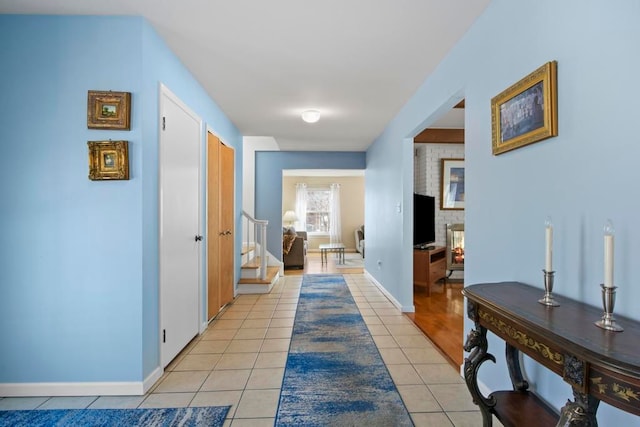 hall with light tile patterned floors, stairs, and baseboards