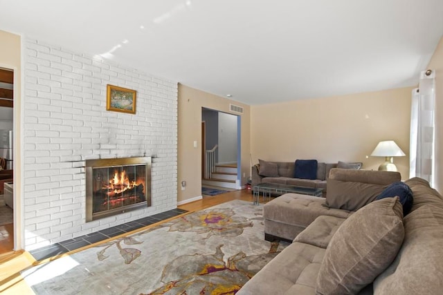 living room with stairs, a fireplace, visible vents, and wood finished floors