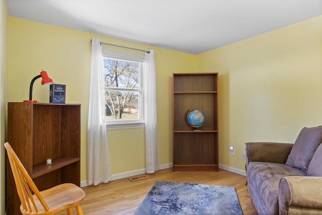 living area featuring baseboards, visible vents, and light wood-style floors