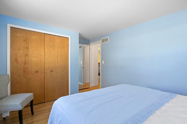 bedroom featuring light wood-style flooring, a closet, and visible vents