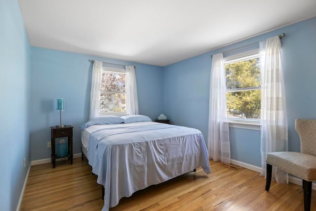 bedroom featuring multiple windows, light wood-style flooring, and baseboards