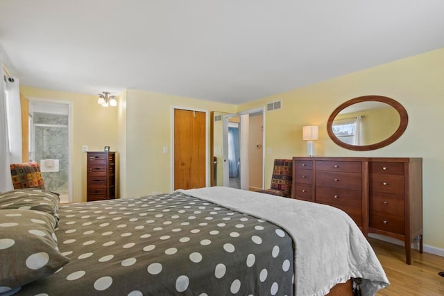 bedroom with light wood finished floors, visible vents, and baseboards