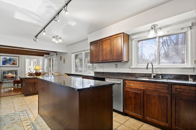 kitchen with light tile patterned floors, a kitchen island, a sink, a brick fireplace, and dishwasher