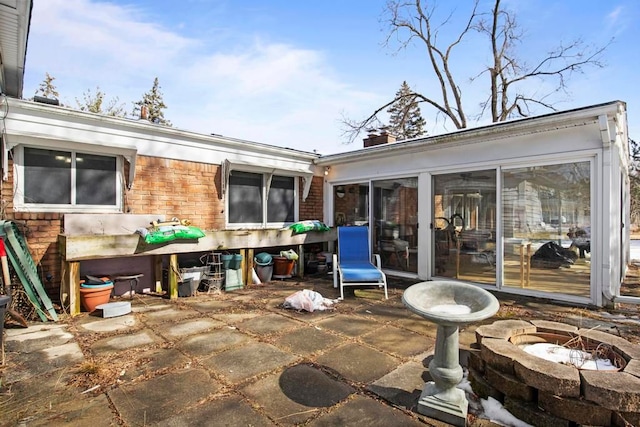 view of patio with a sunroom and a fire pit