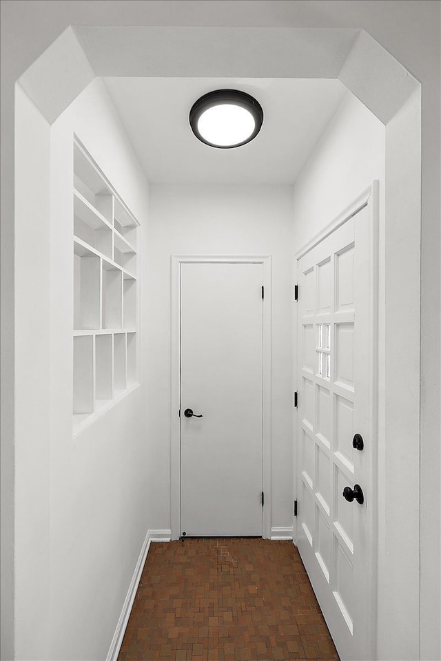 doorway to outside featuring brick floor and baseboards