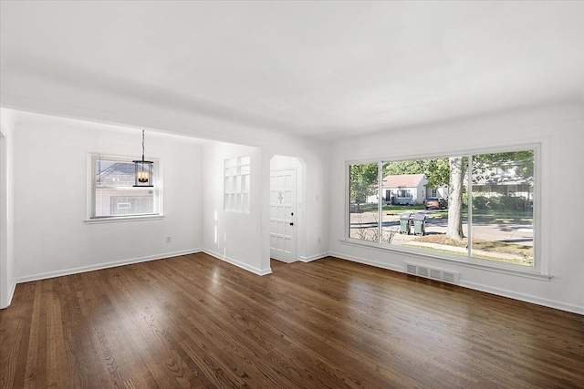 empty room with baseboards, visible vents, and dark wood-type flooring