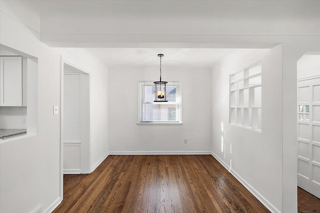 unfurnished dining area with dark wood-style floors and baseboards