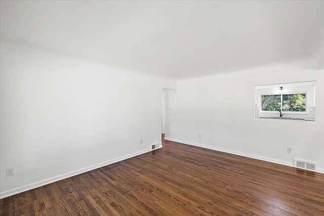 spare room with dark wood-style floors, baseboards, and visible vents