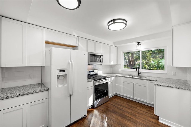 kitchen with dark wood-style flooring, a sink, white cabinets, appliances with stainless steel finishes, and light stone countertops