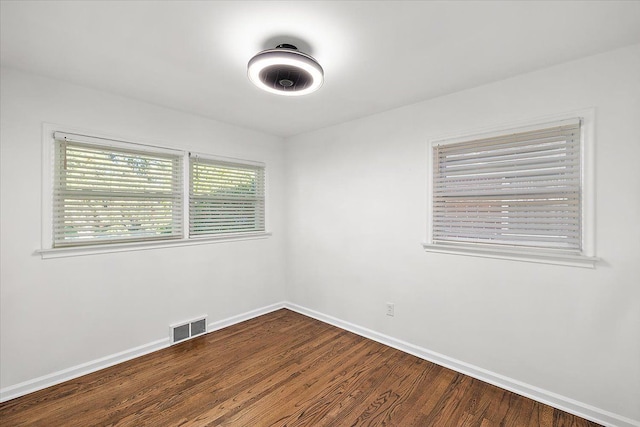 empty room with baseboards, visible vents, and wood finished floors