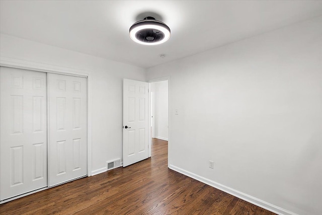 unfurnished bedroom featuring a closet, visible vents, dark wood finished floors, and baseboards