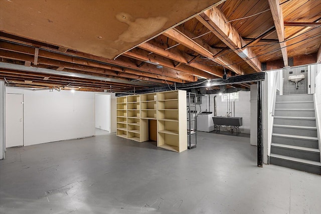 unfinished basement with washer / clothes dryer, a sink, and stairway