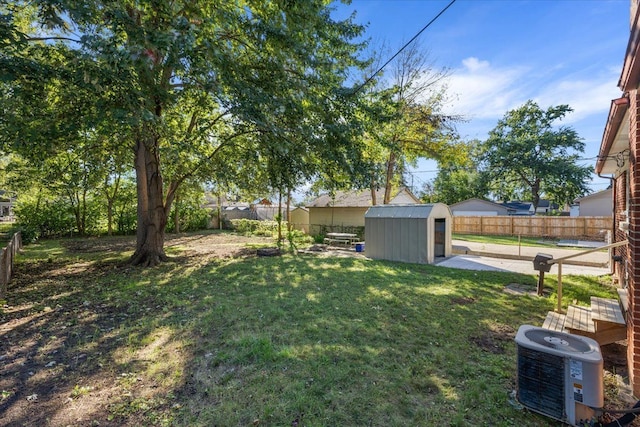 view of yard featuring a storage unit, an outdoor structure, a fenced backyard, and central air condition unit