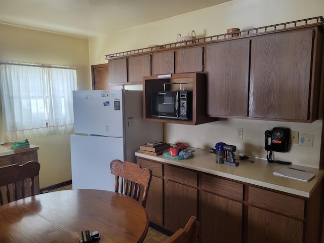 kitchen featuring black microwave, light countertops, and freestanding refrigerator