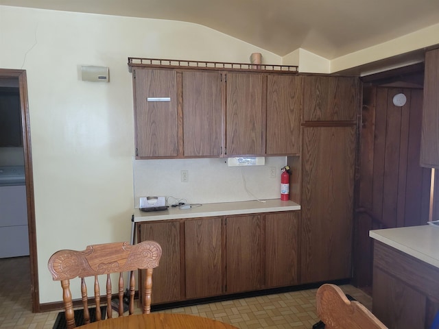 kitchen featuring vaulted ceiling, light countertops, washer / dryer, and decorative backsplash