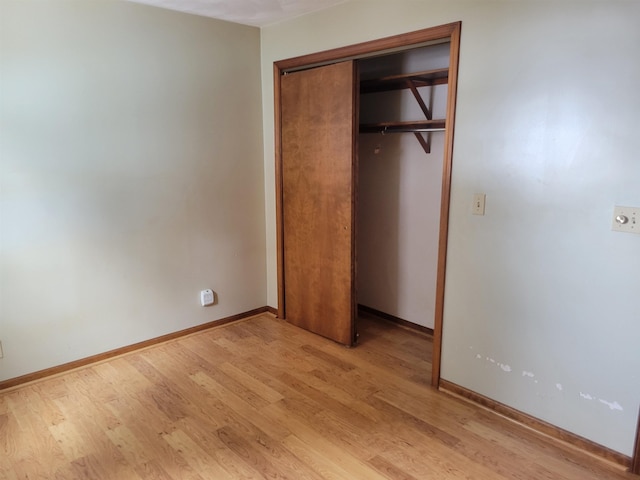 unfurnished bedroom with light wood-type flooring, baseboards, and a closet