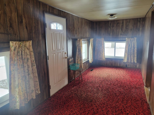 entryway with wood walls, carpet, and visible vents