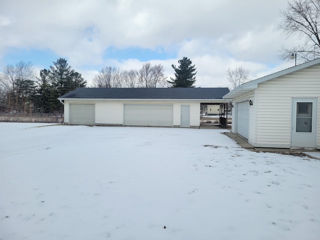 snow covered garage featuring a detached garage