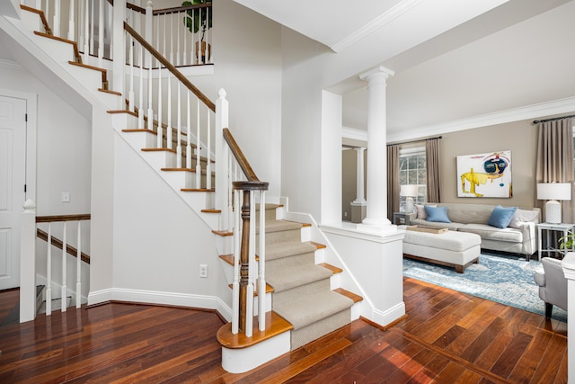 staircase with ornamental molding, decorative columns, baseboards, and hardwood / wood-style flooring