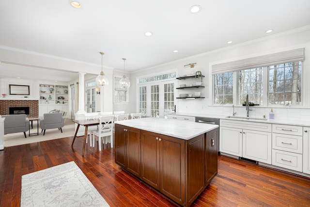 kitchen with a center island, decorative light fixtures, light countertops, ornamental molding, and a sink