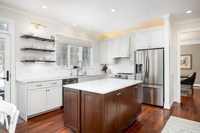 kitchen with appliances with stainless steel finishes, a center island, custom exhaust hood, white cabinetry, and a sink