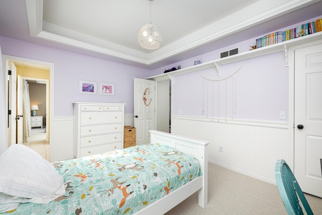 bedroom with wainscoting, a raised ceiling, visible vents, and light colored carpet