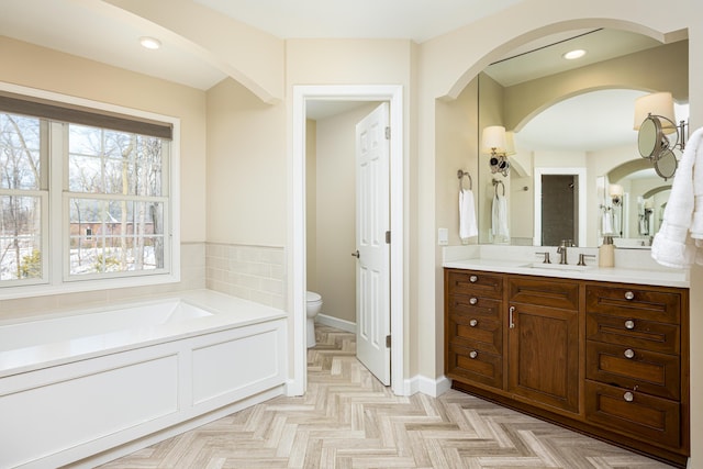 full bath featuring toilet, recessed lighting, vanity, baseboards, and a bath