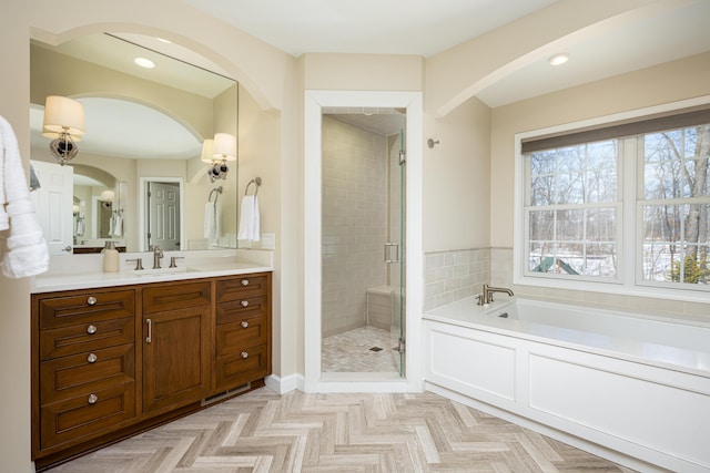 full bathroom with recessed lighting, a garden tub, vanity, and a shower stall