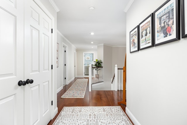 corridor featuring ornamental molding, baseboards, an upstairs landing, and wood finished floors