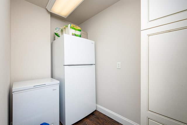 clothes washing area featuring dark wood-style floors, separate washer and dryer, and baseboards