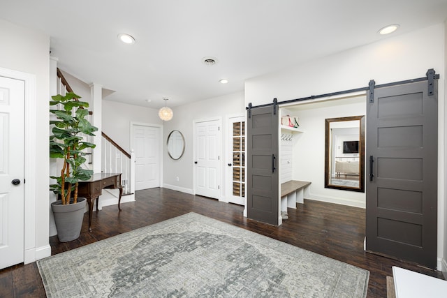 entryway with a barn door, recessed lighting, visible vents, stairs, and dark wood finished floors